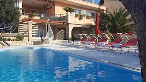 Ein Poolbereich mit Liegestühlen und einer Pergola.