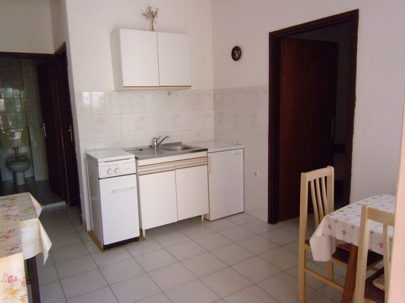 A compact kitchen with white cabinets, a sink, and a small dining area with a table and chairs.