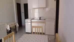 Una cucina compatta con mobili bianchi, un lavandino piccolo e un tavolo con sedie.