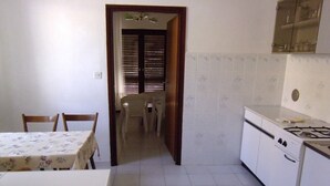 Una cucina con tavolo da pranzo, sedie, piano cottura e pensili.