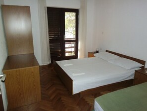 Ein Schlafzimmer mit einem hölzernen Bett, einem Nachttisch, einem Holzschrank und einer Tür zu einem Außenbereich.