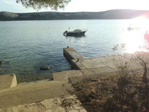 Ein ruhiger See mit einem Bootssteg auf der rechten Seite, umgeben von einem Steg und Treppen, die ins Wasser führen.