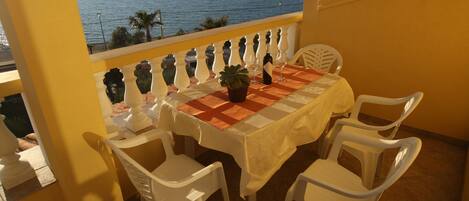 A balcony with a table set for two, overlooking a body of water.