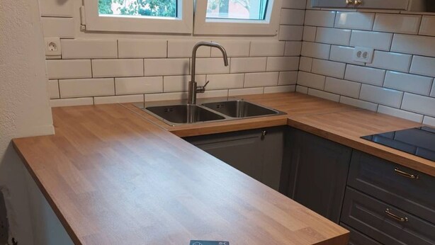 A compact kitchen with a wooden countertop, a built-in sink, and a window above the sink. - Apartments Ana (Pag)