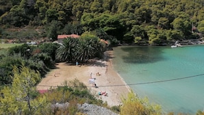 A beach with clear turquoise water, surrounded by dense green forest and hills. - House Linker (Vis)