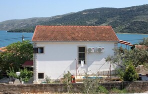 Ein weißes Gebäude mit roten Ziegeln auf dem Dach, zwei Klimaanlagen, einem kleinen Fenster und einer Tür.