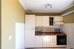 Una cocina compacta con armarios blancos, estufa, fregadero y horno empotrado.