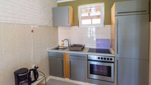 A compact kitchen with a built-in oven, a sink, and a window above the countertop. - Apartments Lapa (Tisno)