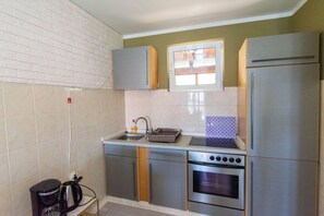 A compact kitchen with a built-in oven, a sink, and a window above the countertop. - Apartments Lapa (Tisno)