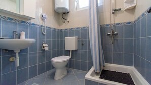 A bathroom with a toilet, sink, shower, and tiled walls. - Apartments Lapa (Tisno)