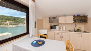 Una cocina compacta con vista al agua, un microondas, una estufa y un lavamanos.