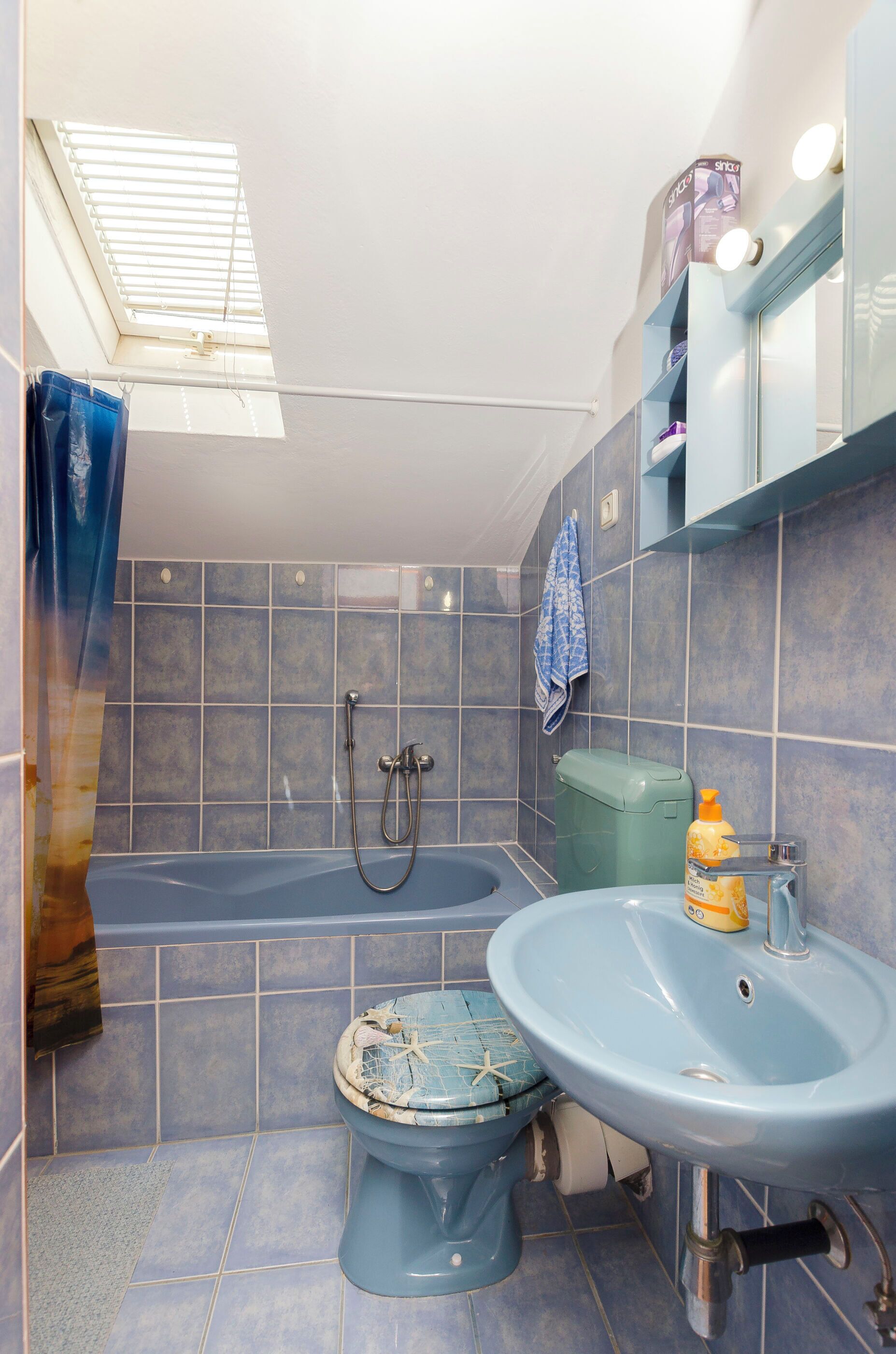 Een badkamer met een bad, toilet en wastafel, alles in blauwe tinten.