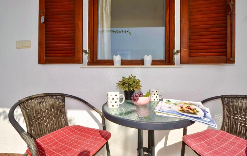 A dining area with a round table, two wicker chairs, a potted plant, and a menu on the table.