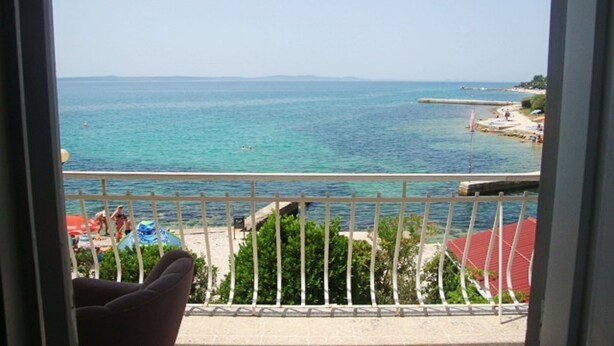 A balcony with a view of the sea, a beach, and a flag. - Apartment Andri (Zadar)