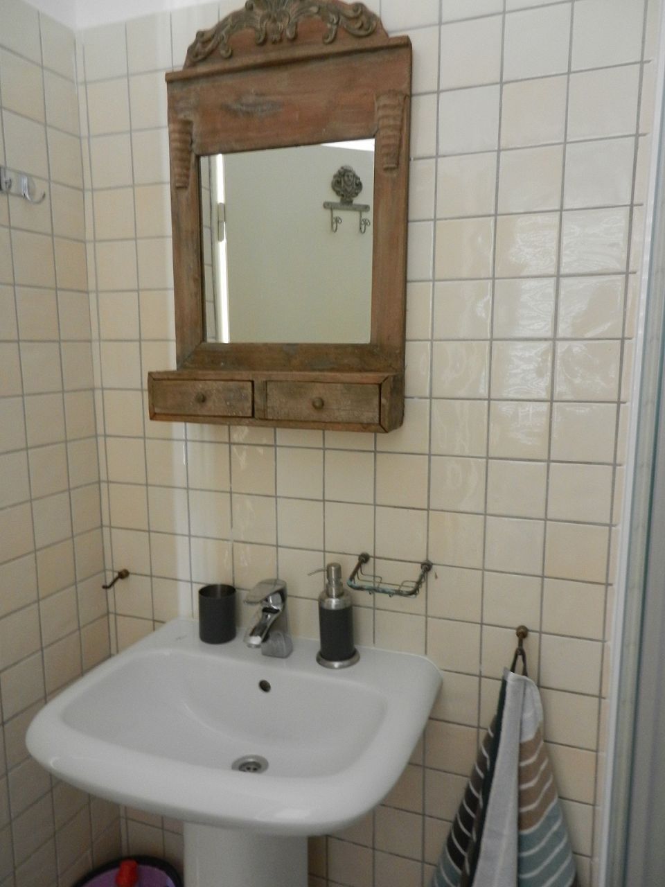 Une salle de bain avec un lavabo blanc, un miroir encadré en bois et une serviette suspendue à un porte-serviettes.