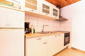 A kitchen with white cabinets, a Bosch coffee maker, a sink, and an oven. - Apartments Durda (Sali)