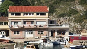 A multi-story building with a red roof, a balcony, and a marina with boats. - Apartments Durda (Sali)