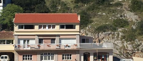 Um edifício de vários andares com telhado vermelho, varanda e um cais com barcos.