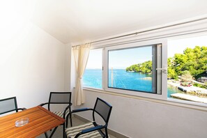 A room with a table and chairs, a window with a view of a body of water and greenery. - Apartments Durda (Sali)