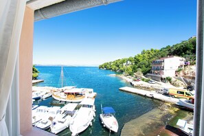 A coastal marina with boats docked, a clear blue sky, and buildings on the hillside. - Apartments Durda (Sali)