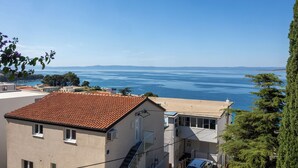 A coastal building with a tiled roof, a balcony, and a view of the sea. - Apartments Josip (Baska Voda)
