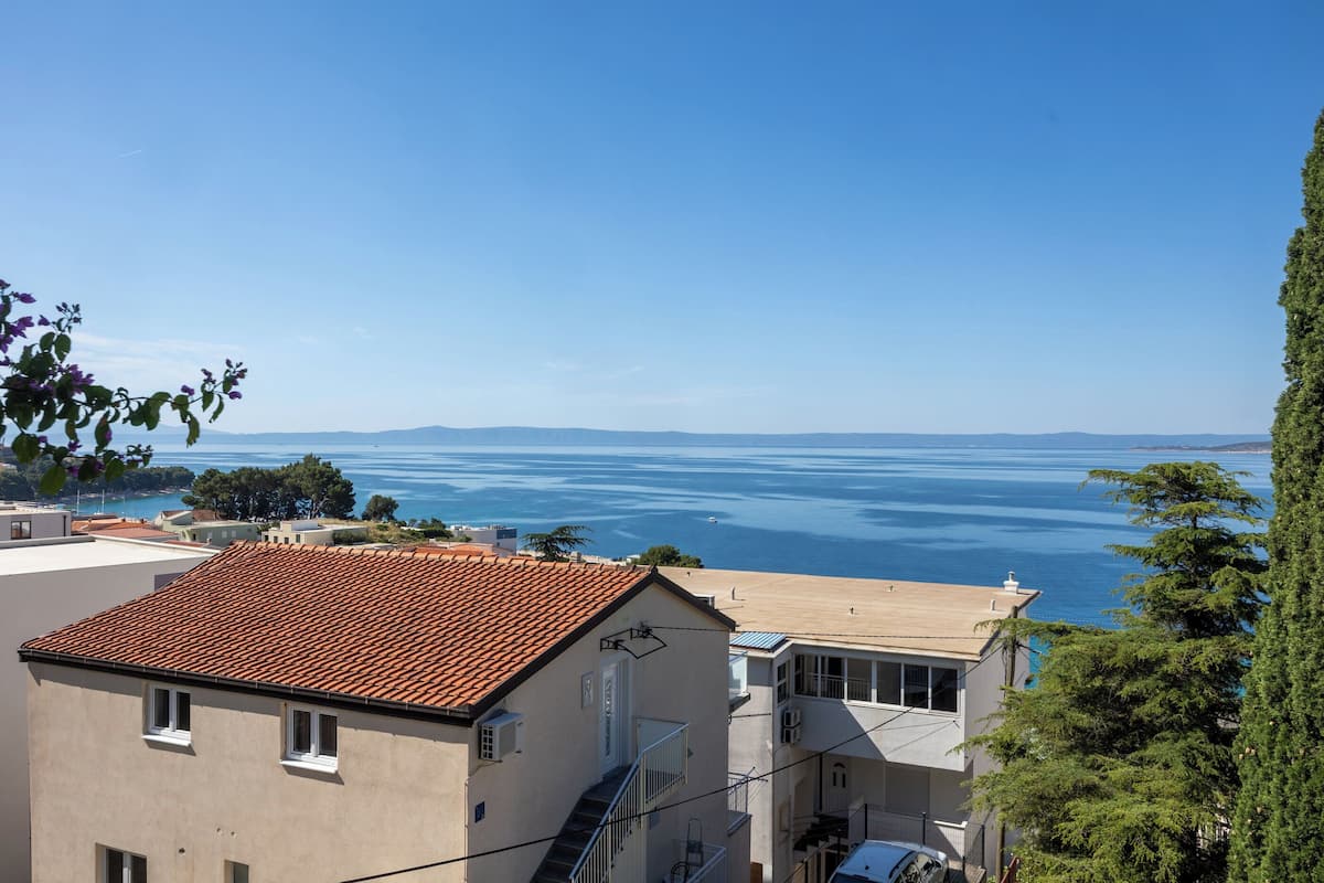 A coastal building with a tiled roof, a balcony, and a view of the sea.