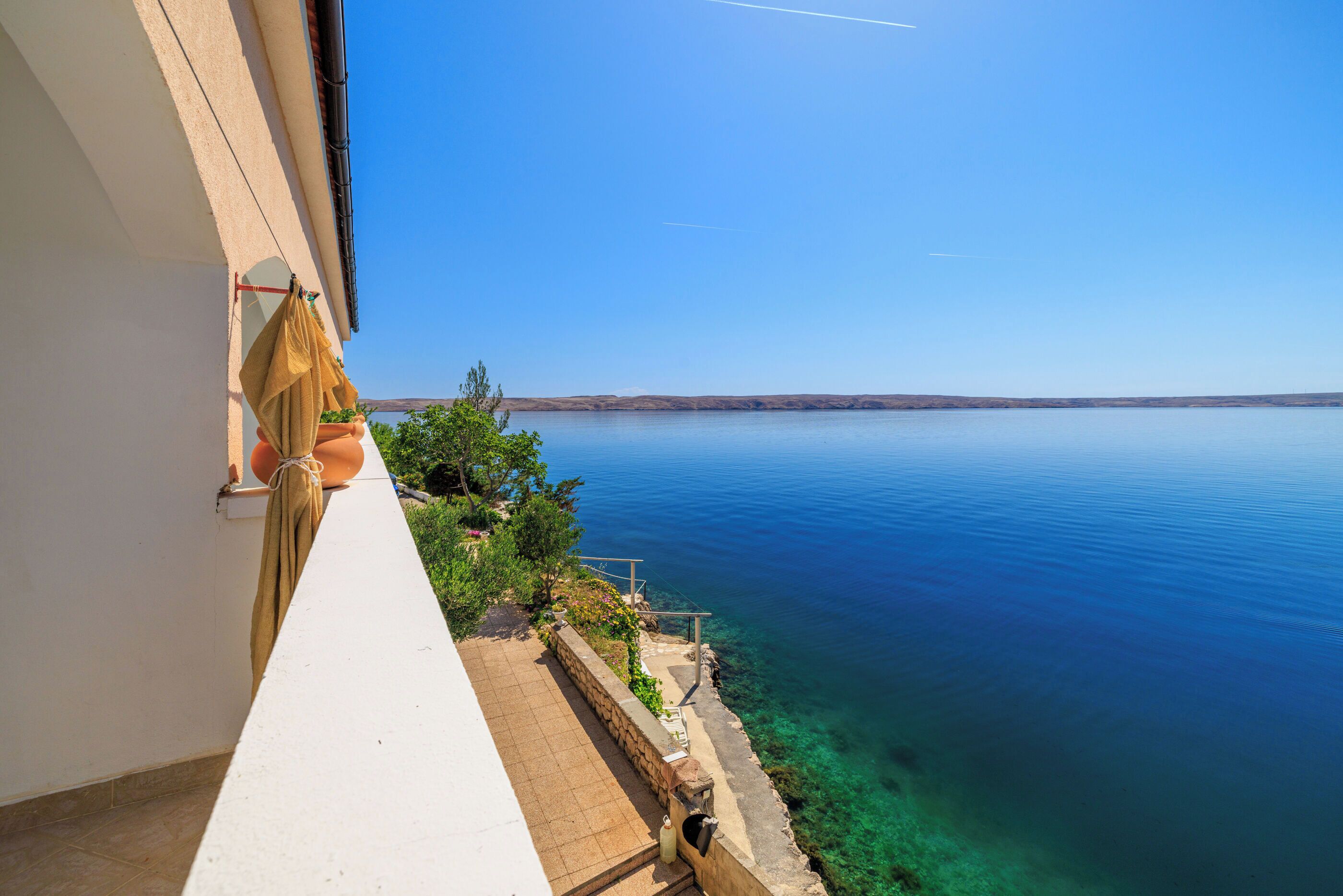 A balcony with a clear view of a calm sea and distant land.