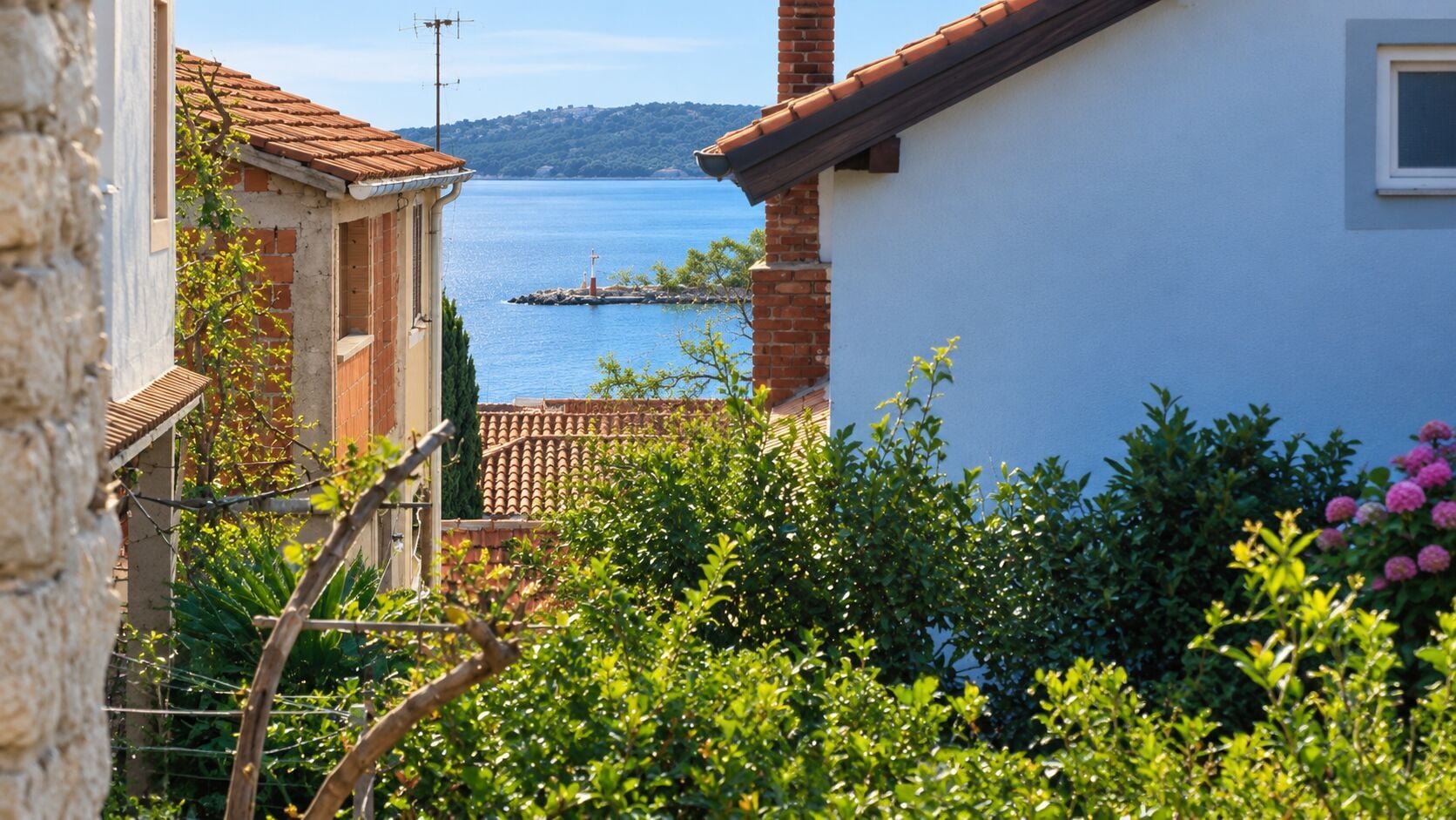 A coastal view with a building, a clear sky, and a body of water.