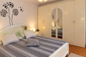 Quarto com cama, mesas de cabeceira, guarda-roupa e decorações nas paredes.