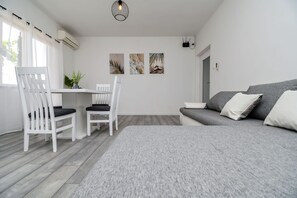 A modern, minimalist room with a grey sofa, two white chairs, a small table, and three wall art pieces. - Apartments Gabi i Miki (Trogir)