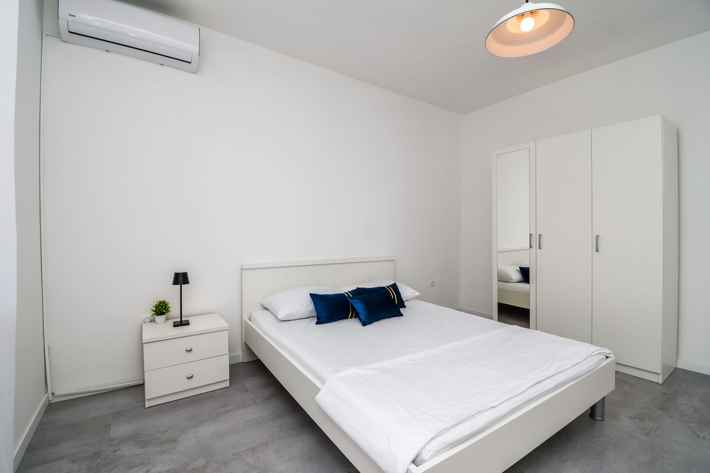 Un dormitorio con cama, mesita de noche, lámpara y armario.
