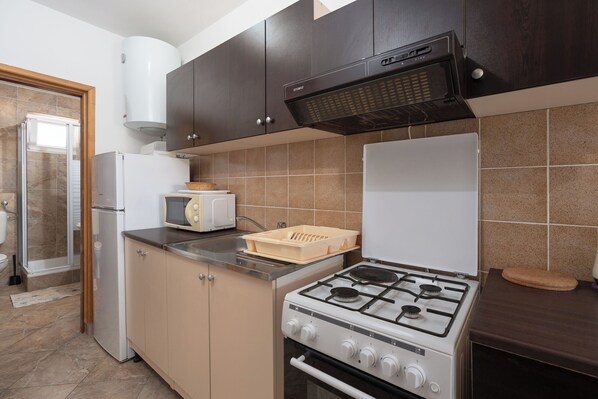 Una cucina compatta con piano cottura a gas, forno a microonde e forno ventilato.