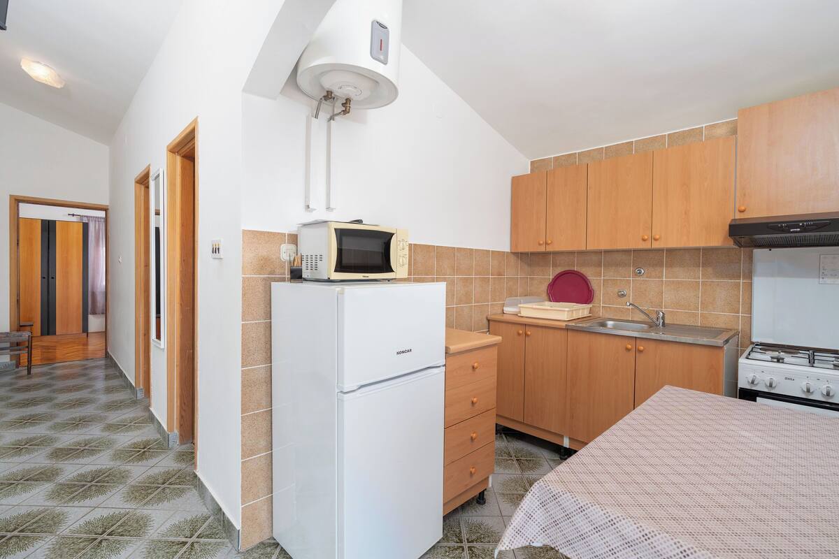A compact kitchen with a refrigerator, microwave, sink, and stove.