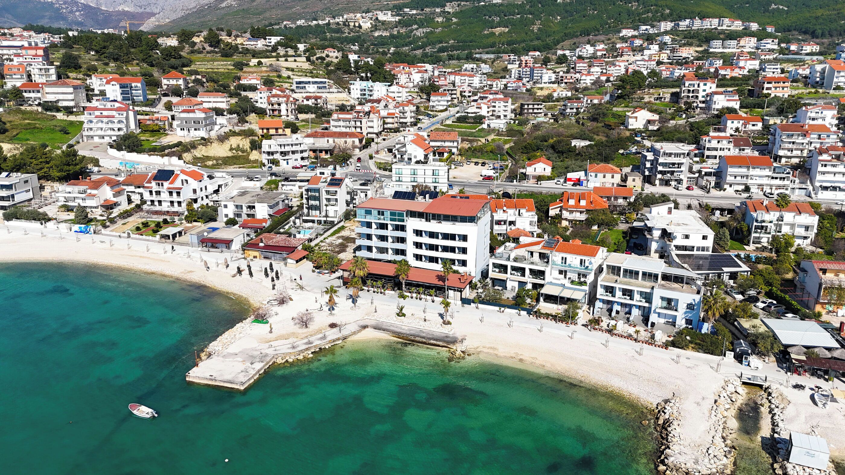 An aerial view of a coastal town with a beach, buildings, and a pier.
