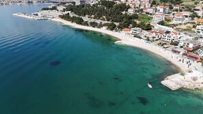 Luftaufnahme einer Küstenregion mit einer Marina, einem Sandstrand und Wohngebäuden.