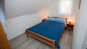 Camera da letto con un letto singolo, due comodini, una finestra con tende e un condizionatore d'aria a muro.