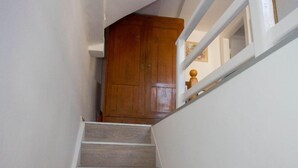 Una scala in legno con pareti bianche e una porta di legno in alto.
