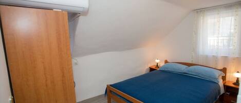 Un dormitorio con cama, armario de madera y equipo de aire acondicionado.