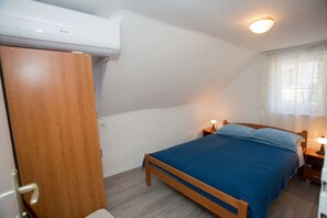 A bedroom with a bed, wooden wardrobe, and an air conditioning unit. - Apartment Bozo (Split)