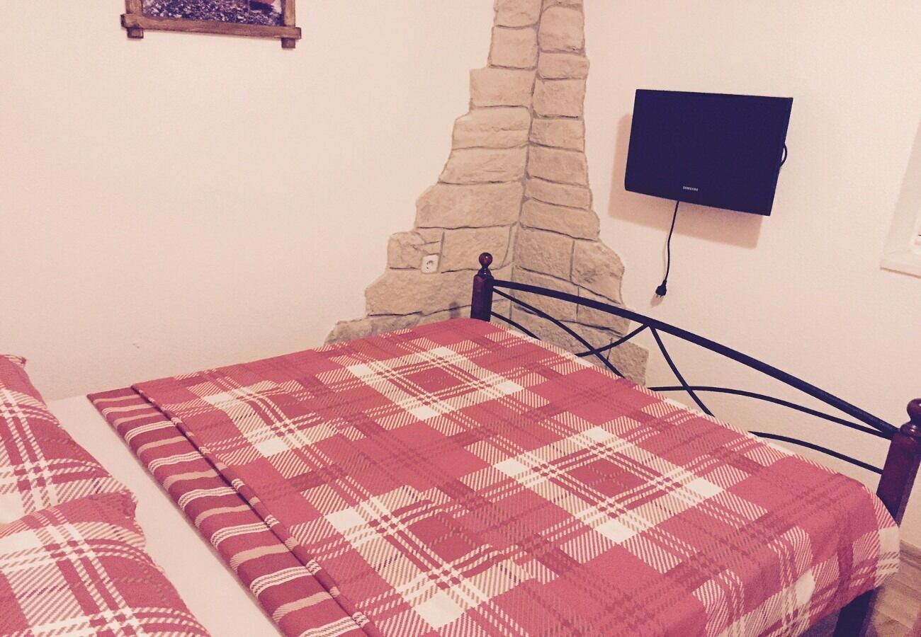 Un dormitorio con una cama, una pared de piedra y un televisor montado.