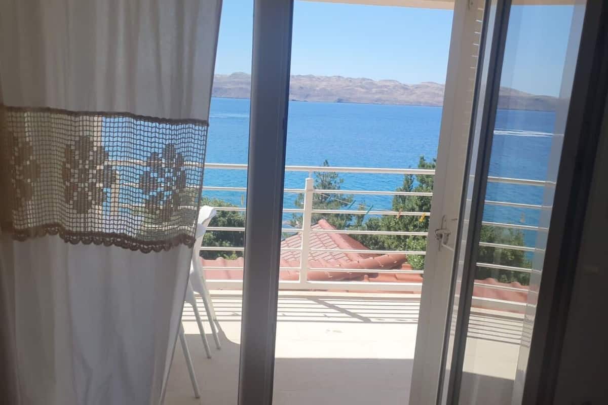 A balcony with a view of the sea and mountains.