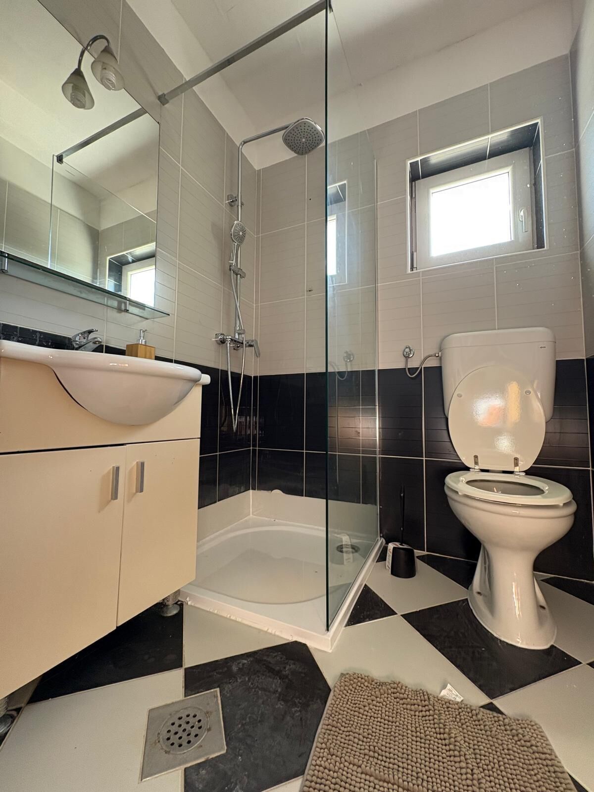Ein modernes Badezimmer mit einer gläsernen Duschkabine, einer weißen Toilette und einem beige gefärbten Waschtisch.