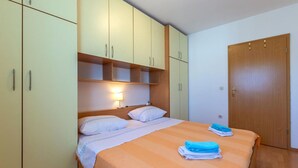 A bedroom with a bed, two bedside tables, a nightstand, a wardrobe, and a door. - Apartment Mare (Trogir)