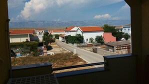 A view through an arched window of a residential area with houses, a road, and mountains in the background. - Apartments Vanja (Vir)