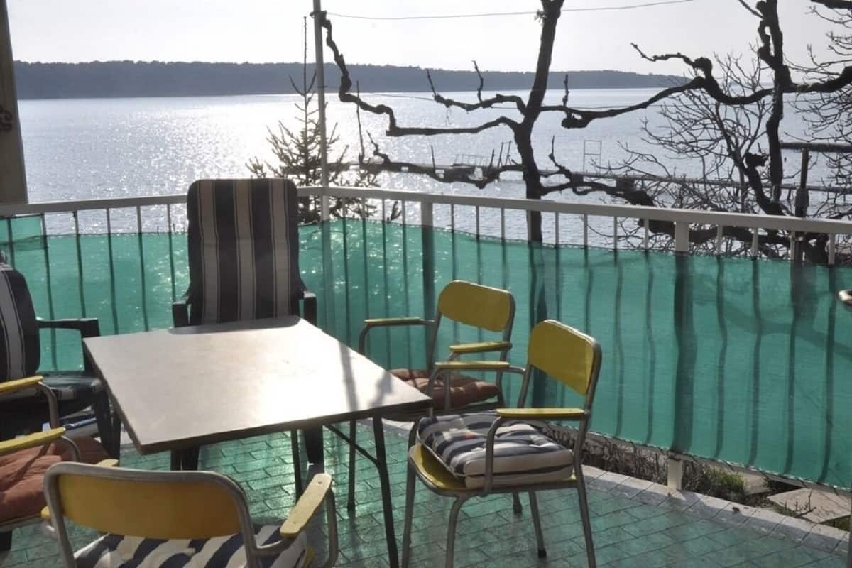 A balcony with a table and chairs, overlooking a body of water.
