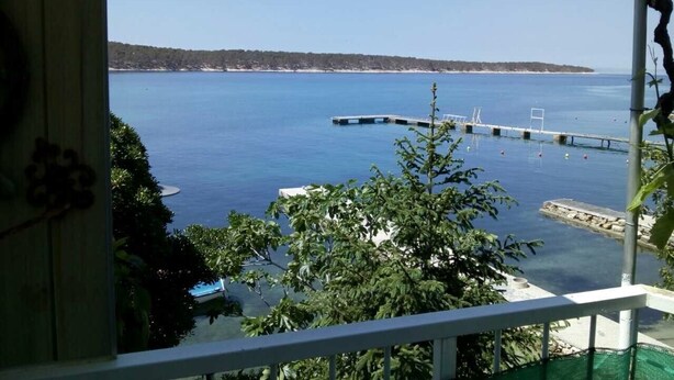 Vista de una zona costera con cielo despejado, un muelle que se adentra en el agua y una costa distante.
