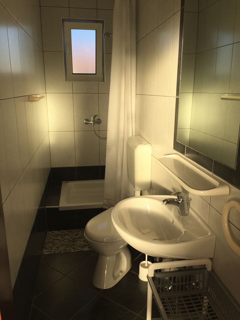 A small bathroom with a toilet, sink, and shower.