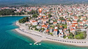 Vue aérienne d’une ville côtière avec une plage, des maisons et une mer bleue et limpide.