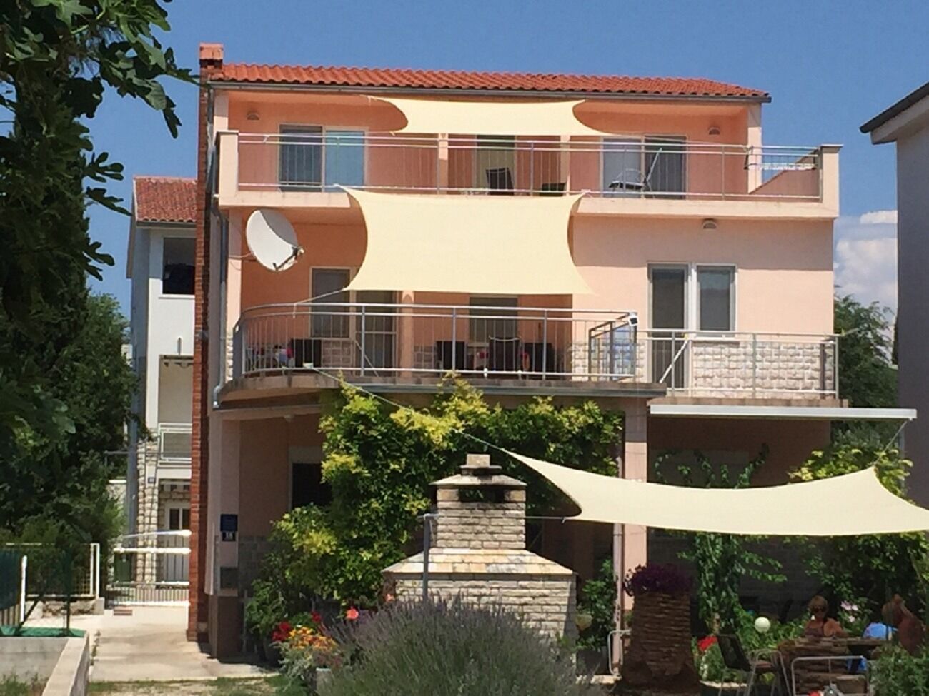 A multi-story building with balconies, a stone fireplace, and outdoor seating.