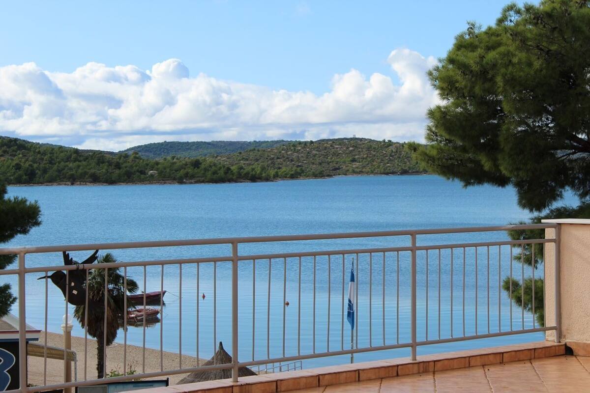 Un balcon donnant sur un lac paisible, entouré d’arbres et de collines.